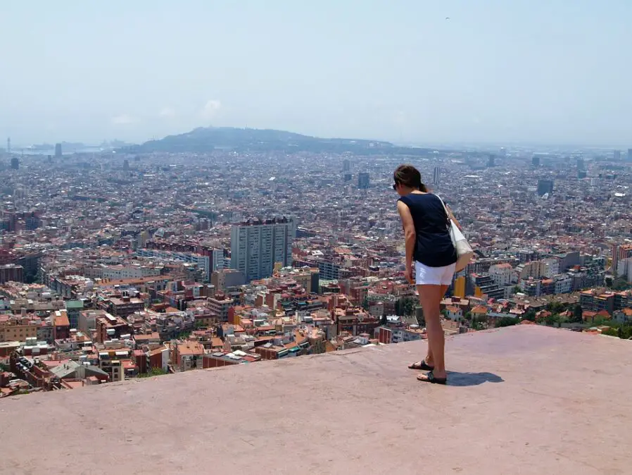 Mujer inclinada en una terraza mirando hacia abajo la panorámica de la ciudad con temor al espacio abierto.