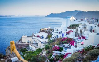 Isla Santorini en el Mar Egeo, casas blancas con flores sobre el acantilado