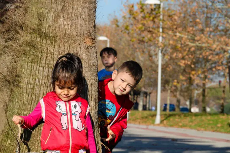 Niños jugando delante y detrás de un árbol adquieren destrezas con juegos predeportivos