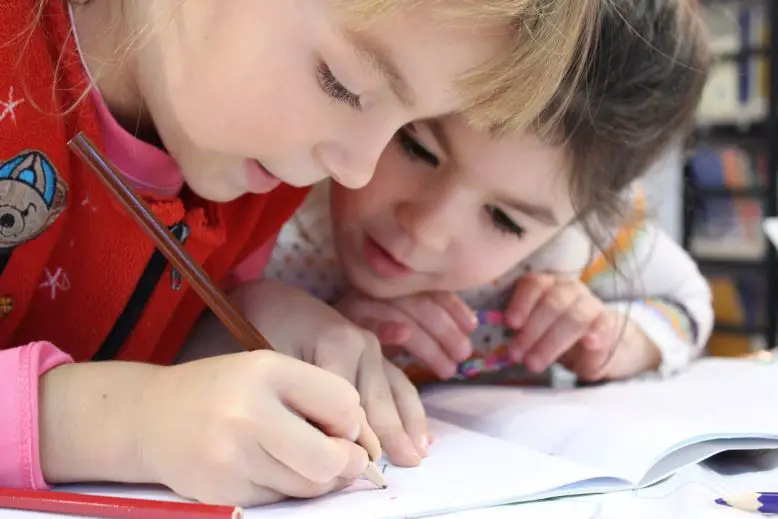 Niño y niña haciendo tarea escolar que refleja el rendimiento académico.