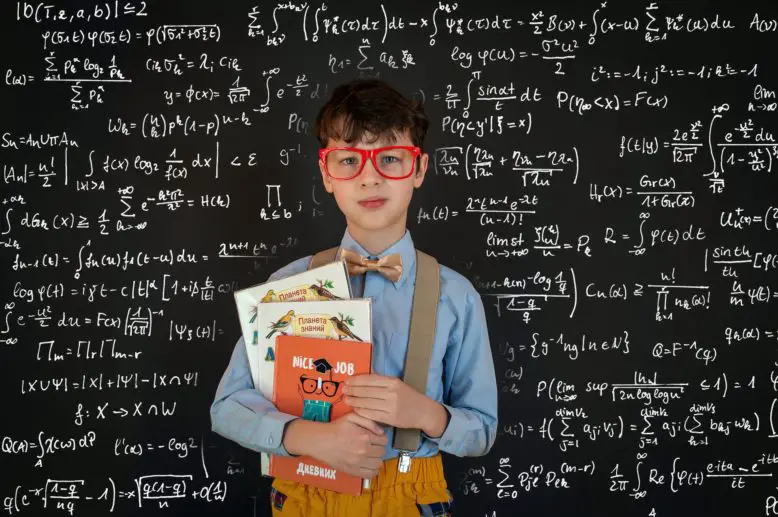 niño nerd en pizarrón lleno de fórmulas matemáticas